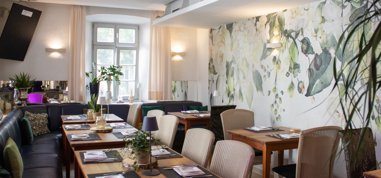 Landhotel Zum Schwanen Gemütlicher Gastraum mit floral gestalteter Wand, liebevoll gedeckten Tischen und heller Wohlfühlatmosphäre.