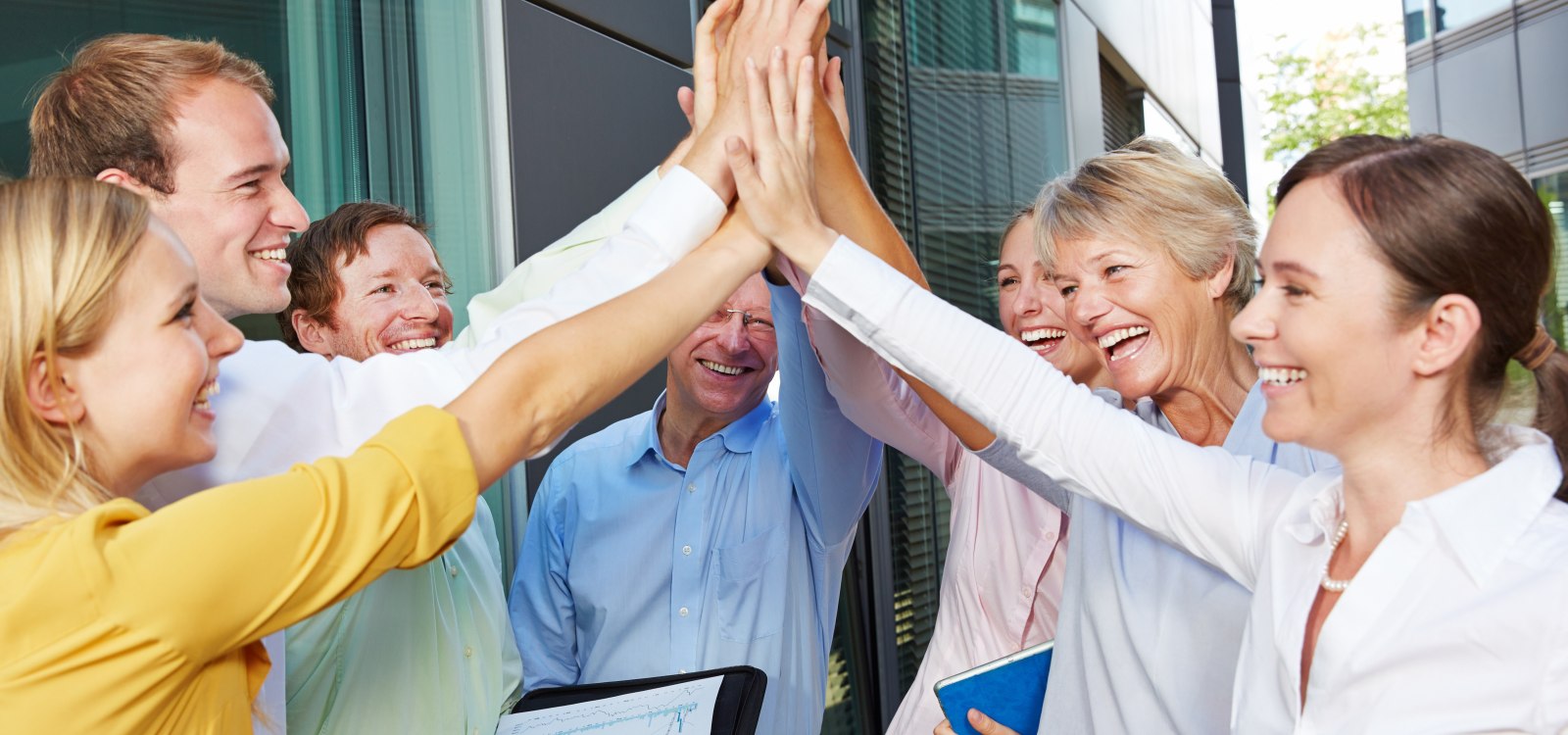 Miteinander in Rheinhessen Erfolgreiches Business-Team feiert gemeinsam Erfolge mit High-Five vor Bürogebäude