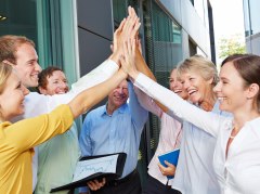 Miteinander in Rheinhessen Erfolgreiches Business-Team feiert gemeinsam Erfolge mit High-Five vor Bürogebäude