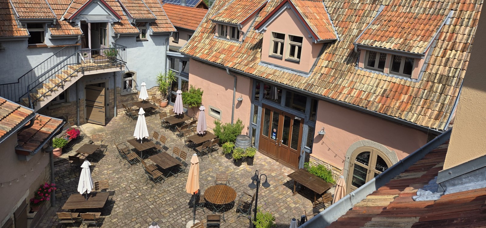 Historischer Kulturhof Eckelsheim mit sonnigem Innenhof, Sitzgelegenheiten und mediterranem Flair.