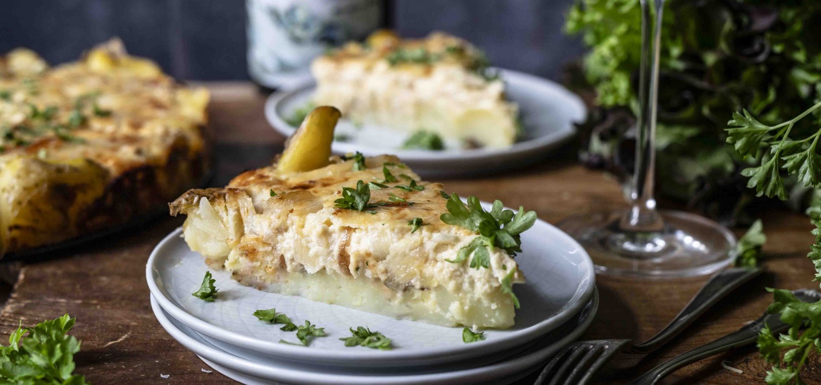 Zwiebelkuchen mit Quetschkartoffeln mit frischen Kräutern, serviert mit Weißwein – regionaler Genuss aus Rheinhessen.