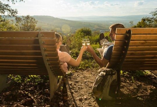 Wanderpaar auf Wanderliegen mit Wein, © Dominik Ketz