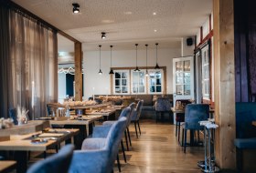 Modernes Restaurant mit stilvoll gedeckten Tischen, Kerzenlicht und gem&uuml;tlichem Ambiente.