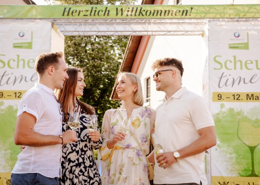 Zwei junge Paare mit Weinglas vor dem Eingang zur Scheu time